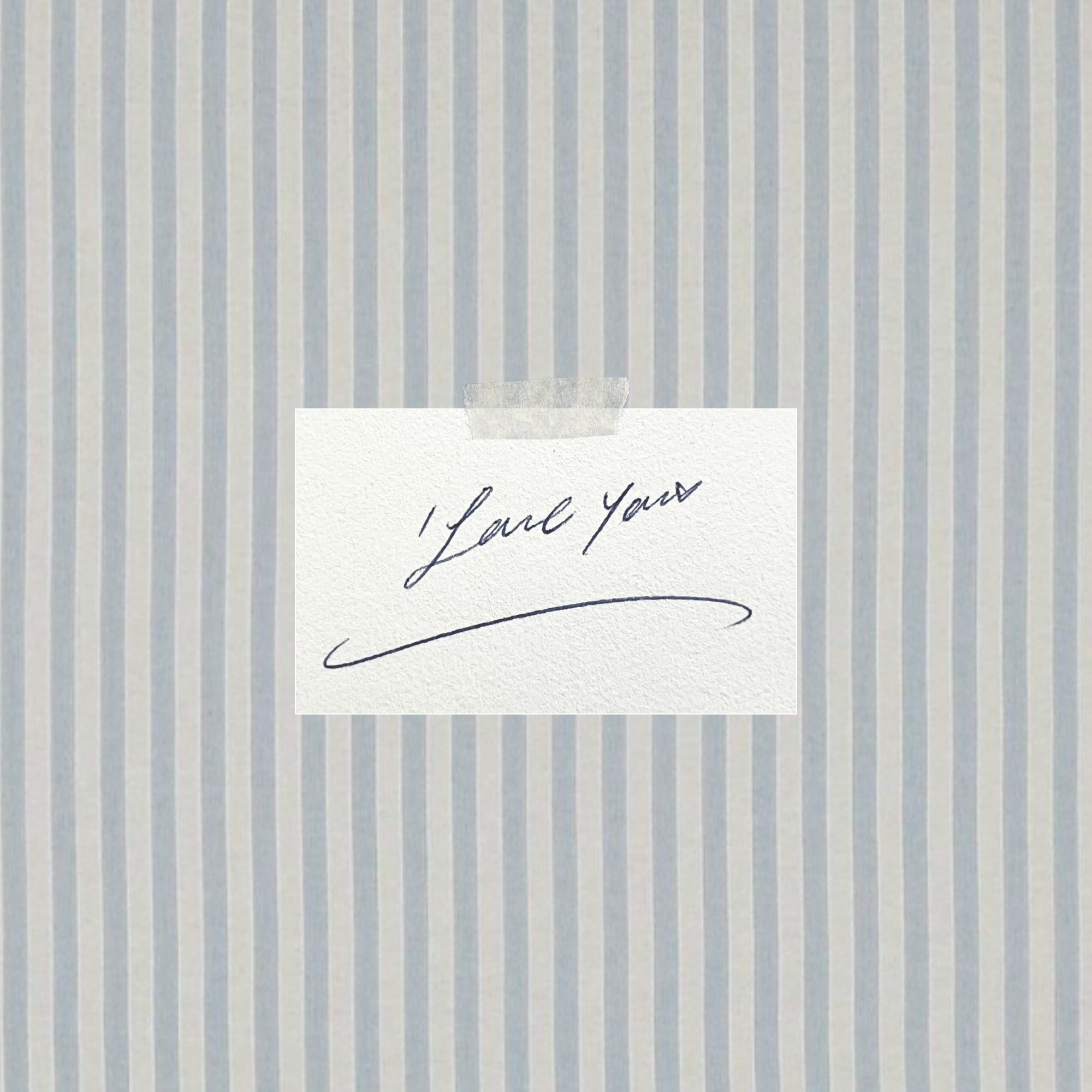 A small white card with a handwritten script reading 'Love You' taped against a light blue and white vertically striped background.